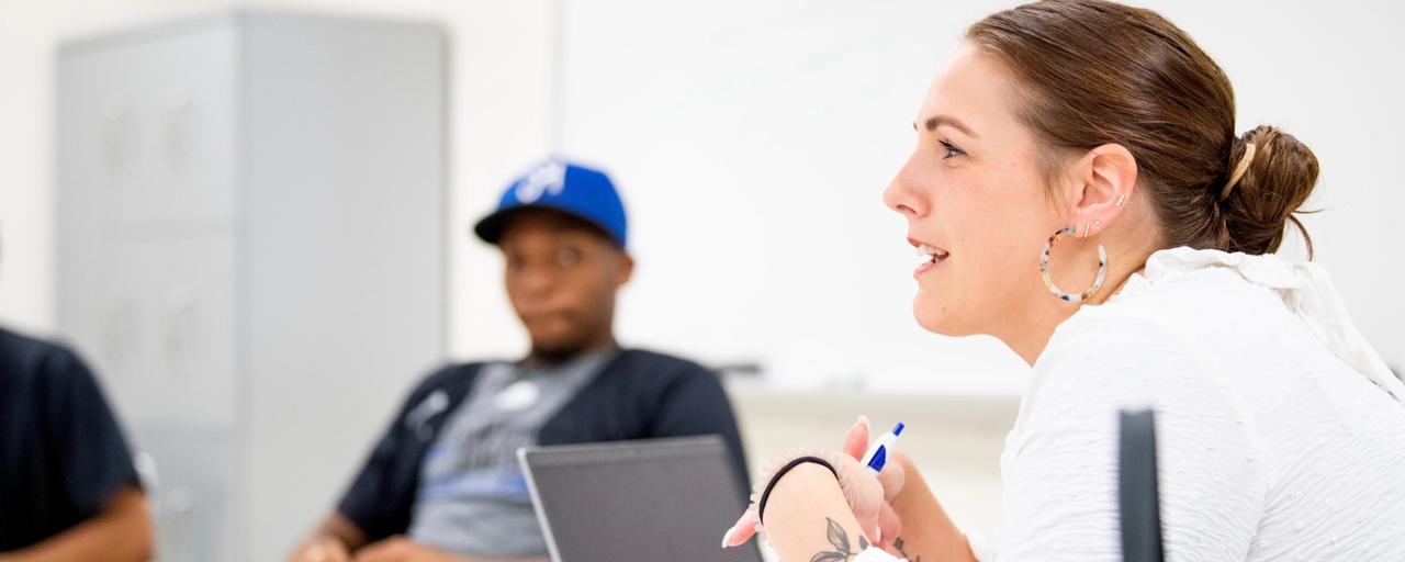 2 students in a classroom with one working on a computer